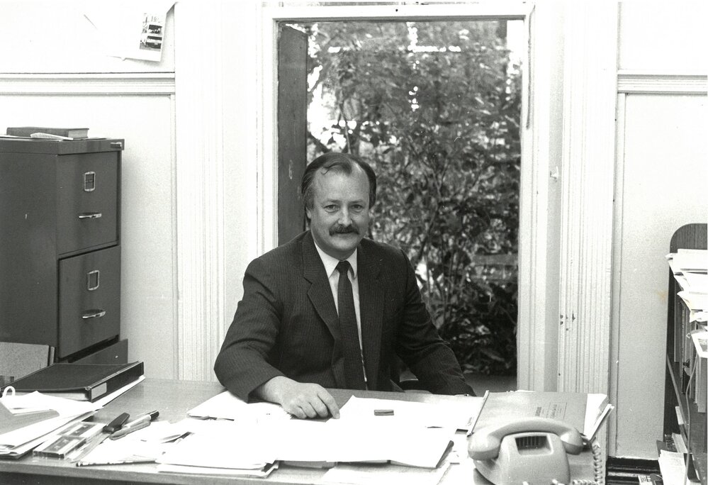 David Morgan seated at desk, 1986