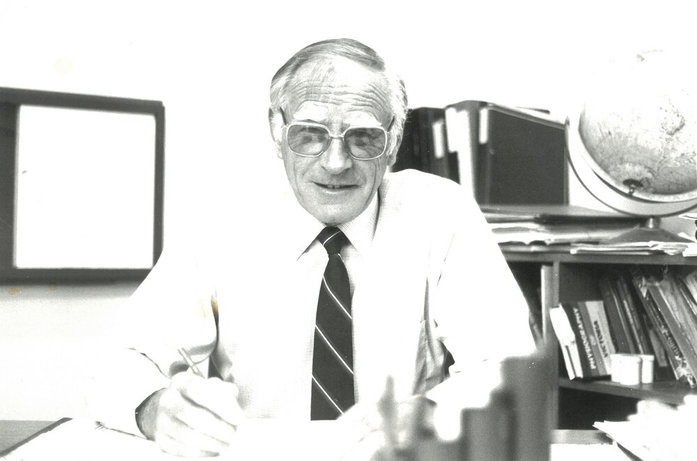 John Allan seated at desk, 1990