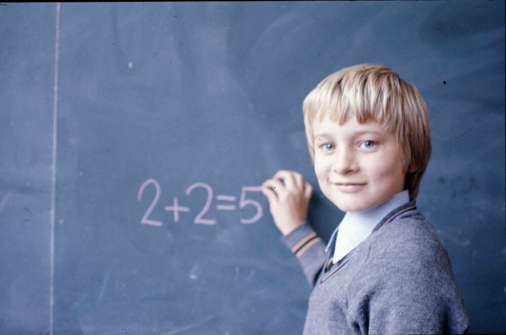 Junior School boy writing equation on the blackboard in chalk, 1974