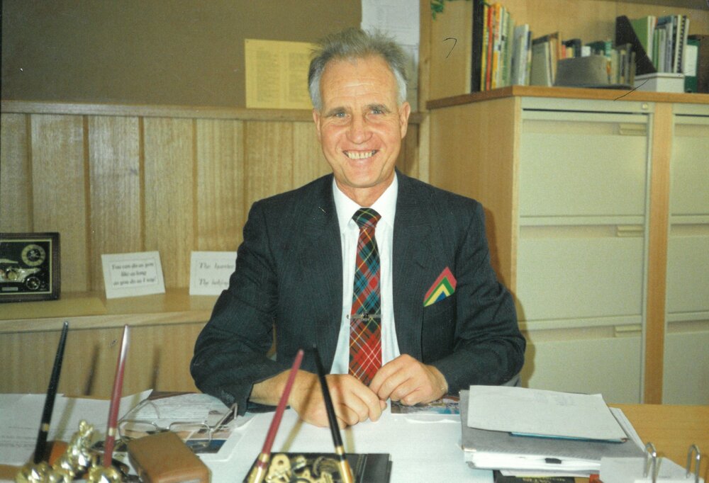 Don Brown seated at desk in his office, 1990