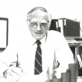 John Allan seated at desk, 1990