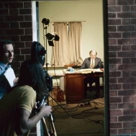 Arthur Sandell seated at desk in an office, 1974