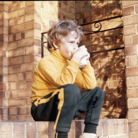 Junior School student sitting on step and drinking from cup, 1974