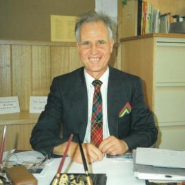 Don Brown seated at desk in his office, 1990
