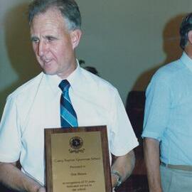 Mr Don Brown holding award recognising his 32 years dedicated service to the school, 1990