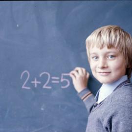Junior School boy writing equation on the blackboard in chalk, 1974