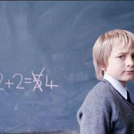 Junior School boy writing equation on the blackboard in chalk, 1974
