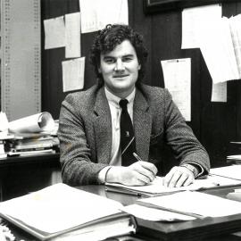 Adrian Collins seated at desk, circa 1990
